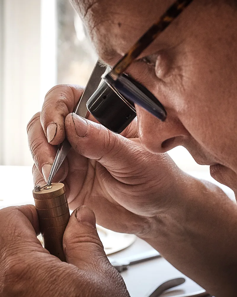 Clockmaker adjusting a precision component using magnification loupe during fine assembly work