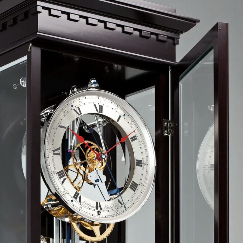 Clock with open door revealing mechanical movement and glass case