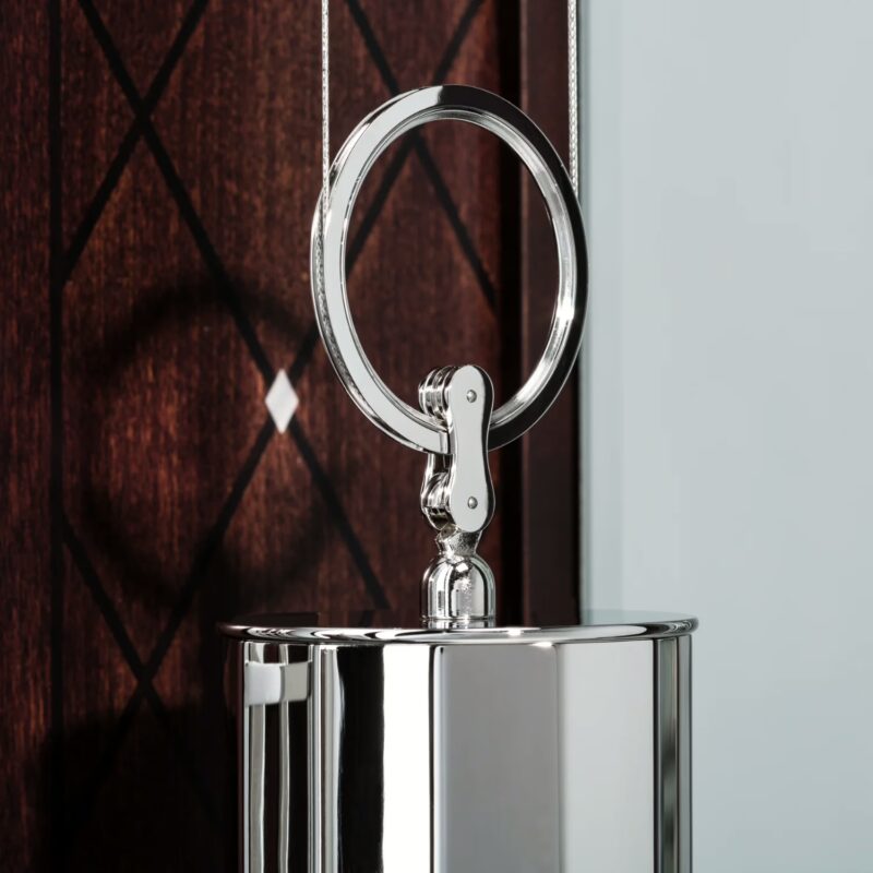 Polished weight and suspension ring detail against inlaid cherry wood panel