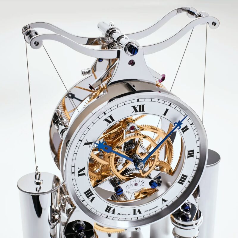 NT 11 Table Clock close-up showing open skeleton dial with Roman numerals, blued hands, and visible gear train