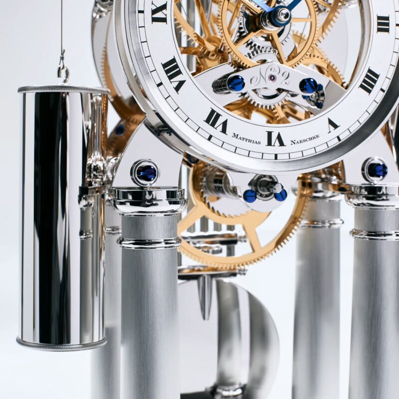 Detailed view of mechanical movement with polished weights, bridges, and intricate gear assembly of luxury table clock